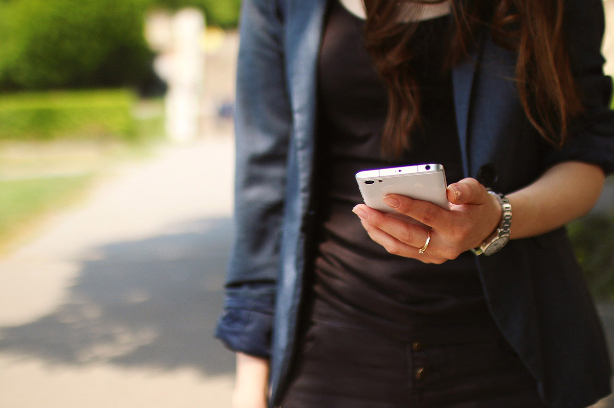 Main d'une femme tenant un téléphone dans la rue