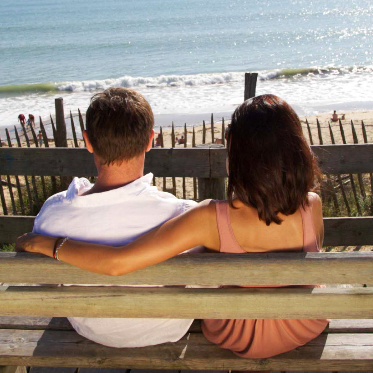 un couple assis sur un banc regarde la mer en Nouvelle-Aquitaine