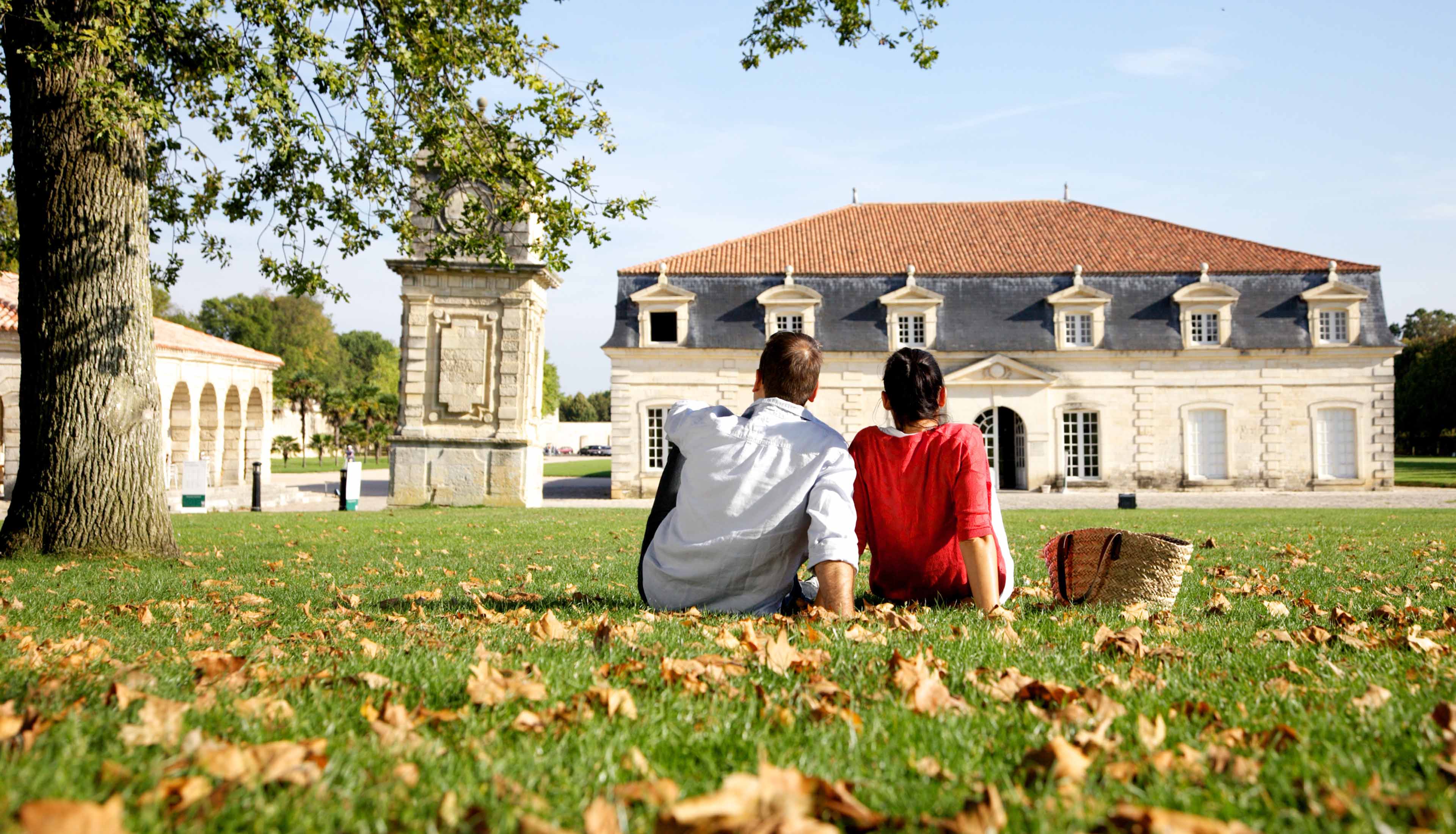 Couple assis dans l'herbe devant un des bâtiment la Corderie royale, à Rochefort