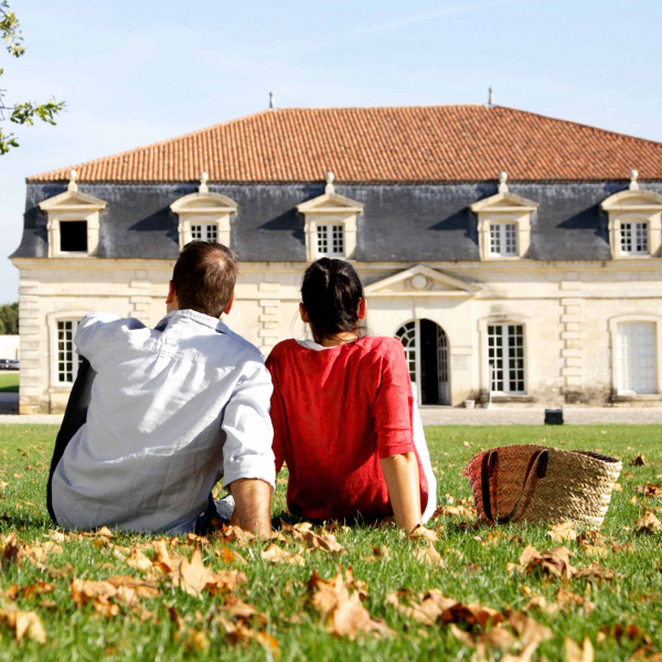 Couple assis dans l'herbe devant un des bâtiment la Corderie royale, à Rochefort